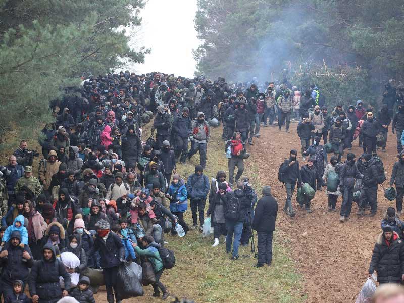 مهاجرون يسيرون باتجاه معبر الحدود البيلاروسية البولندية أمس     (رويترز)