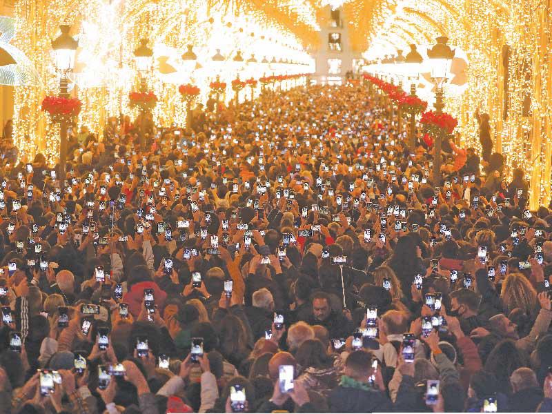 أشخاص يلتقطون صوراً لأضواء عيد الميلاد في شارع ماركيز دي لاريوس بإسبانيا رغم القلق من تفشّي «كورونا» (رويترز)