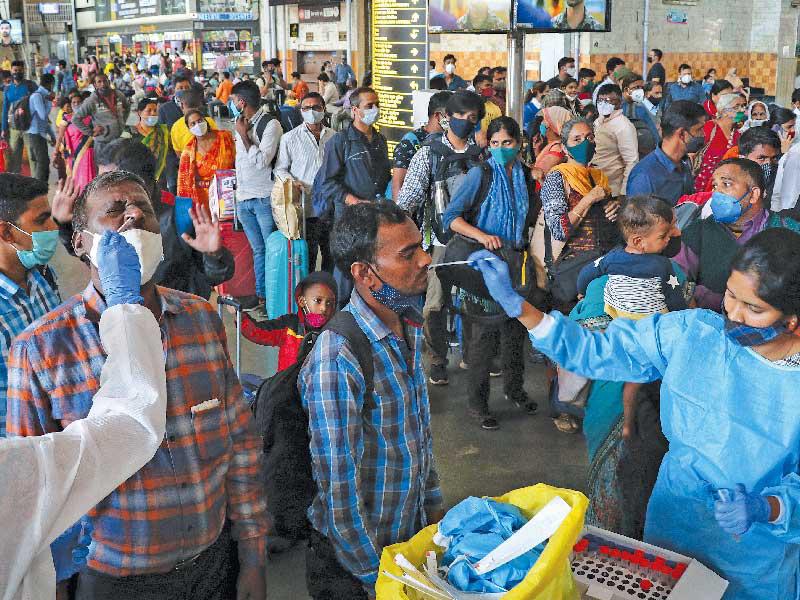 عمال صحة يجرون فحص «بي سي آر» لمسافرين بمحطة قطار في مومباي أمس  (رويترز)