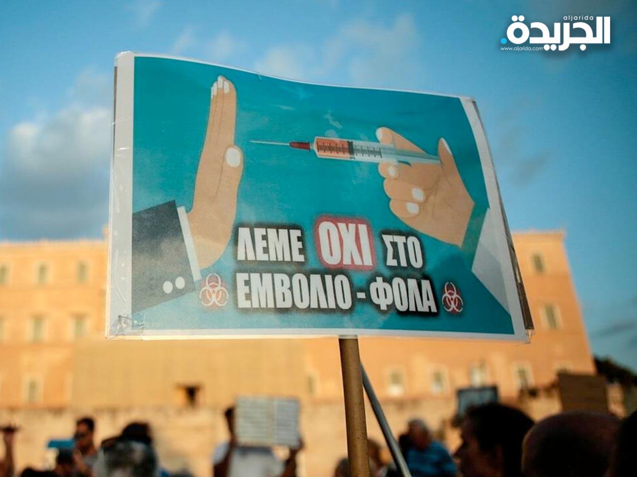 متظاهر يحمل لوحة احتجاج على التلقيح في أثينا، اليونان