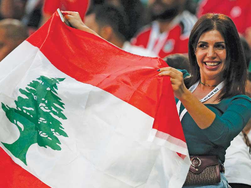 سيدة تحمل العلم اللبناني خلال مباراة كرة القدم بين لبنان ومصر في الدوحة أمس (رويترز)