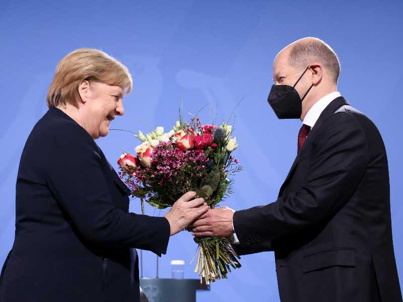 أولاف شولتس مقدّماً باقة ورد وداعية لميركل في المستشارية أمسt(رويترز)