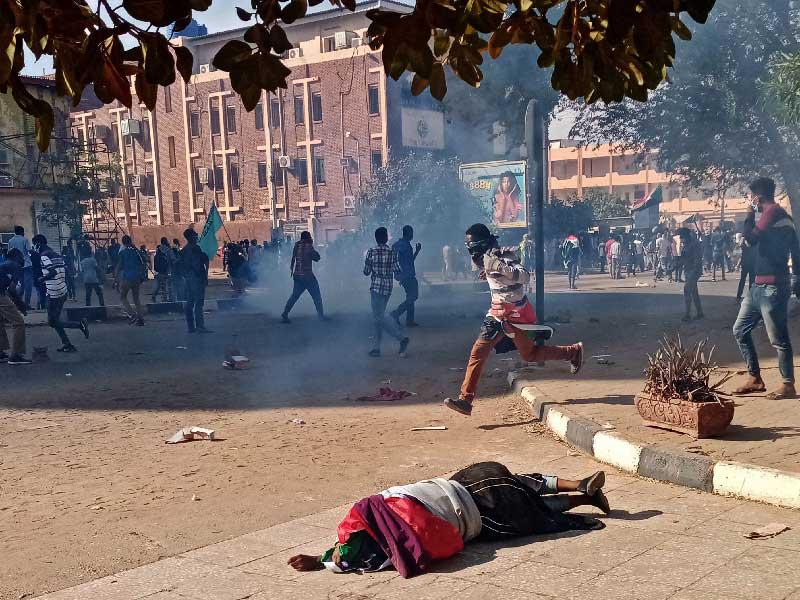 سقوط متظاهر سوداني مصاب على رصيف بعد أن أطلقت قوات الأمن الغاز المسيل للدموع