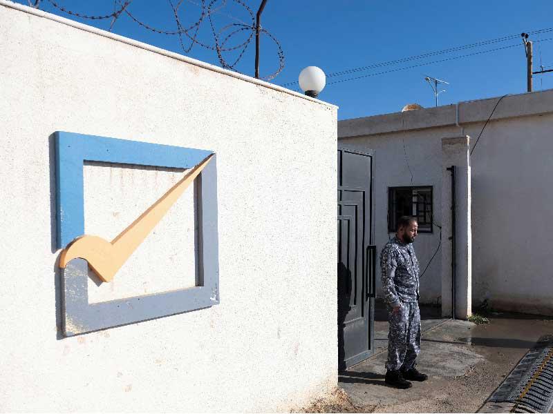 عنصر أمني يقف أمام مبنى المفوضية الوطنية العليا للانتخابات في بنغازي ، ليبيا