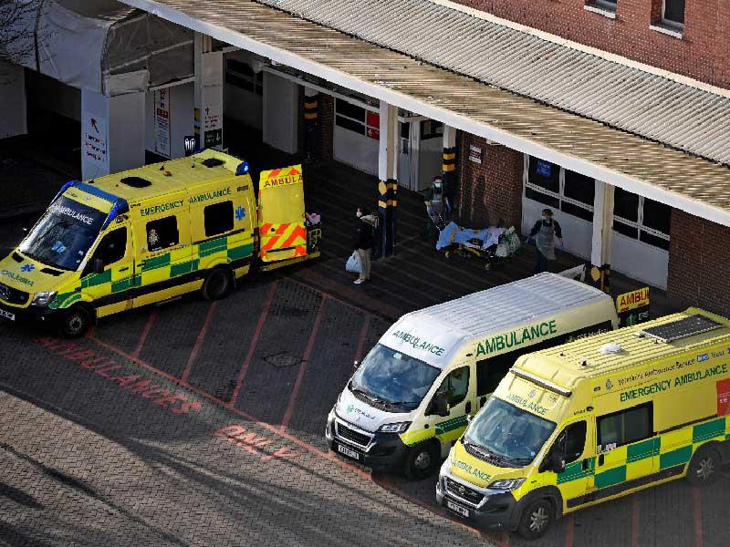 المسعفون ثناء نقل مريض على عربة بجانب سيارات الإسعاف المتوقفة خارج مستشفى