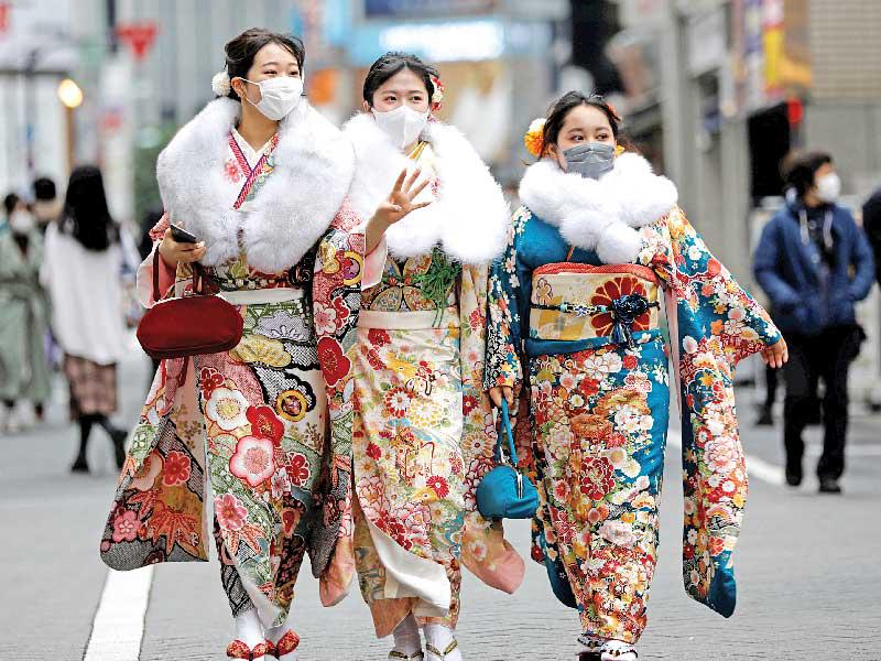 يابانيات يرتدين «الكيمونو» والأقنعة الواقية في طريقهن لحفل بطوكيو أمس (رويترز)