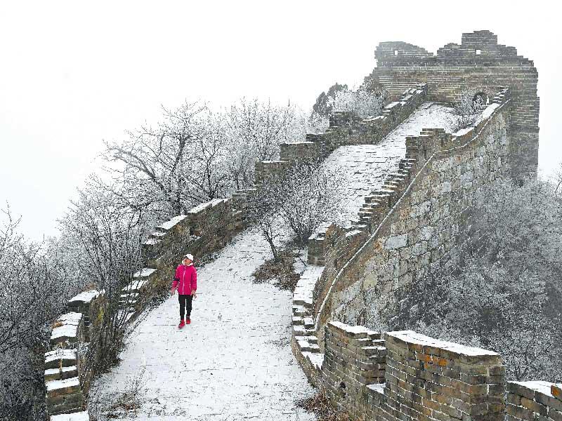 سيدة تسير على سور الصين المغطى بالثلوج في منطقة شمال بكين (أ ف ب)n