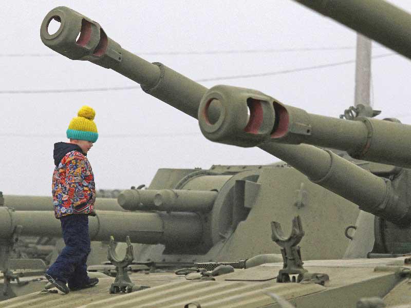 طفل على متن دبابة خلال احتفال  بـ «يوم المدافع عن الوطن» في مدينة سيفاستوبول بشبه جزيرة القرم أمس (رويترز)