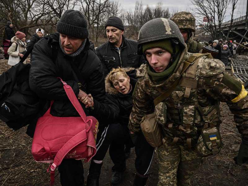 جندي أوكراني ومدنيون يحاولون مساعدة سيدة على عبور جسر مدمّر في مدينة إيربين قرب كييف أمس (أ ف ب)