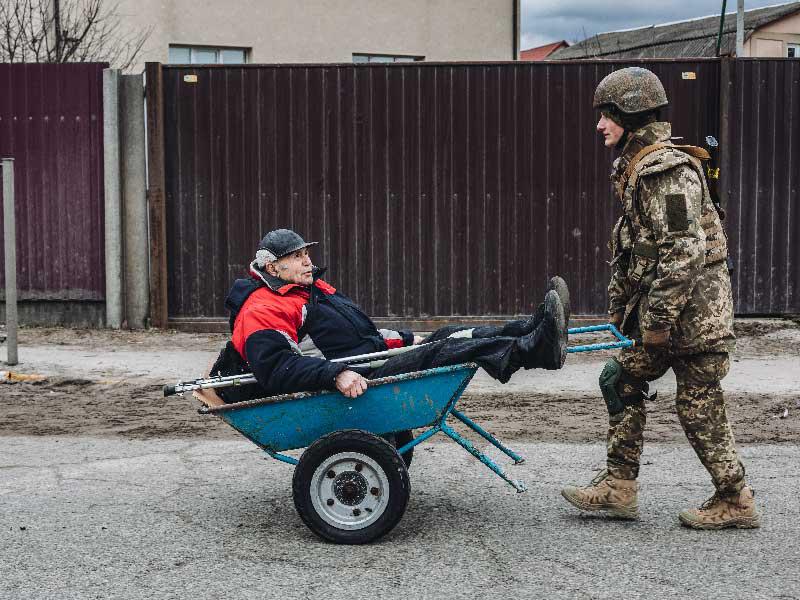 جندي أوكراني ينقل عجوزاً بعربة في إربين اليوم (رويترز)n