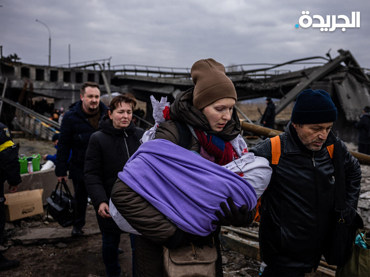 امرأة تحمل طفلها تعبر جسراً مدمراً أثناء فرارهم من مدينة إيربين شمال غرب كييف