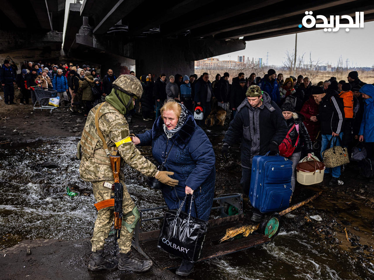 جندي أوكراني يساعد الأشخاص الذين تم إجلاؤهم أثناء فرارهم من مدينة إيربين شمال غرب كييف 