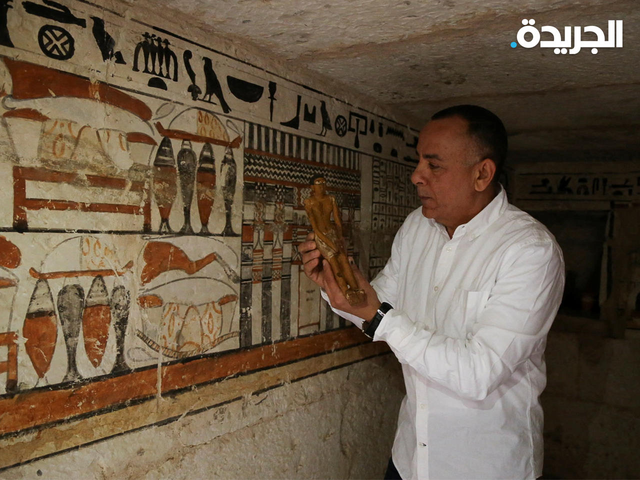 الأمين العام للمجلس الأعلى للآثار مصطفى وزيري يعرض تمثالاً صغيراً في مقبرة اكتُشفت في منطقة سقارة