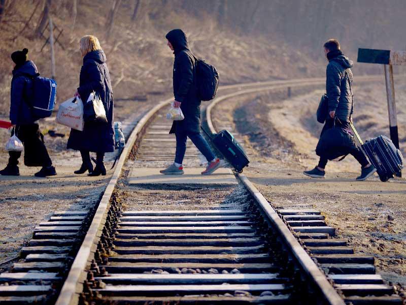لاجئون أوكرانيون يجتازون سكة حديد بعد عبورهم إلى بولندا أمس (د ب أ)