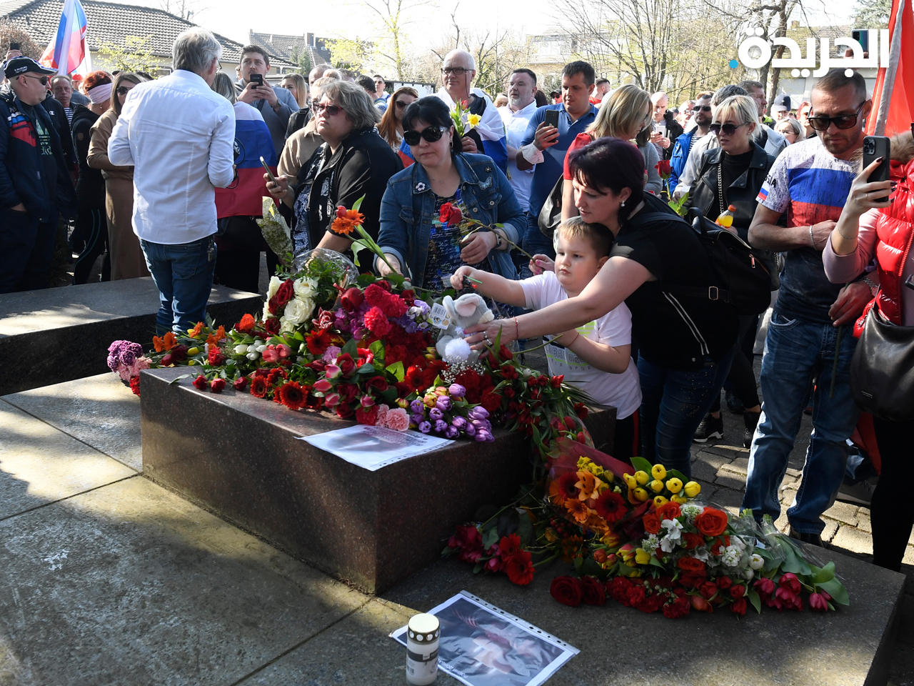 المشاركون في المسيرة يضعون زهور على نصب تذكاري سوفيتي