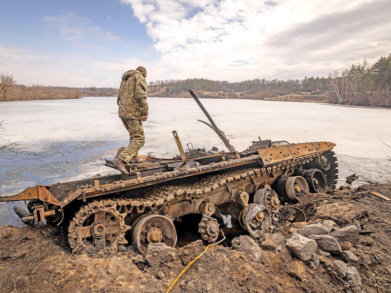 جندي أوكراني على دبابة روسية مدمرة شمال شرق البلاد (أ ف ب)