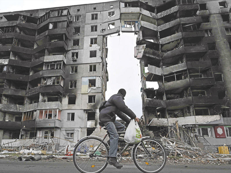 أوكراني على دراجته الهوائية يمرّ قرب أبنية مدمّرة في مدينة بوروديانكا جنوب غربي كييف (أ ف ب)