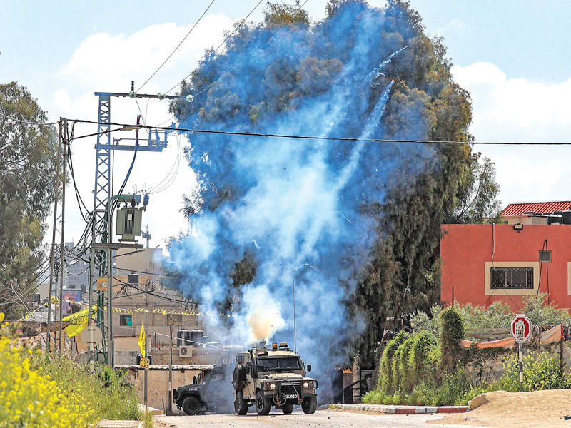 مدرعة إسرائيلية تطلق قنابل الغاز خلال اقتحام جنين أمس (أ ف ب)
