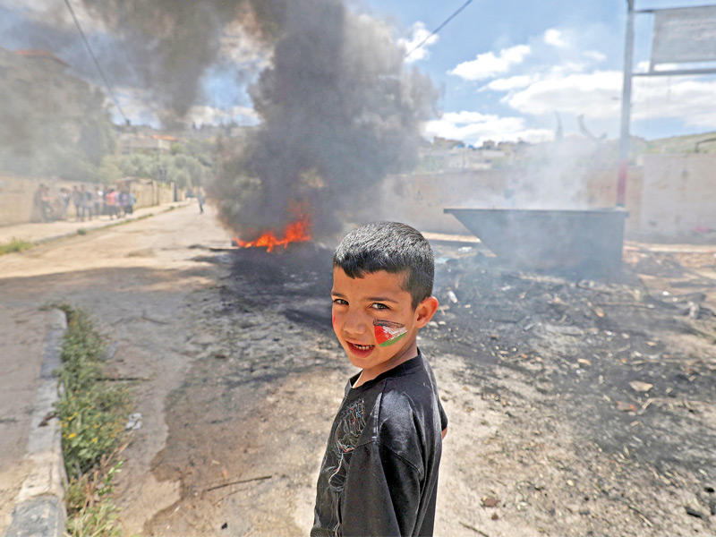 صبي فلسطيني أمام إطارات مشتعلة في مخيم جنين أمس الأول (أ ف ب)