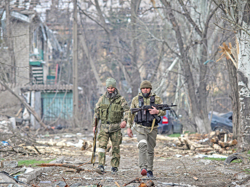 مقاتلان شيشانيان وسط أبنية متضرّرة بالقصف في ماريوبول (رويترز)