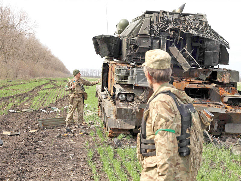 جنديان أوكرانيان قرب دبابة روسية مدمّرة في قرية غوزاروفكا في خاركيف (أ ف ب)