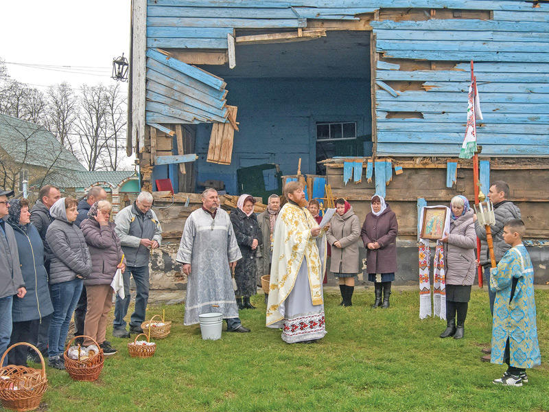 أوكرانيون يصلّون أمام كنيسة متضررة بالقصف الروسي في قرية بيريموها قرب كييف  (رويترز) 