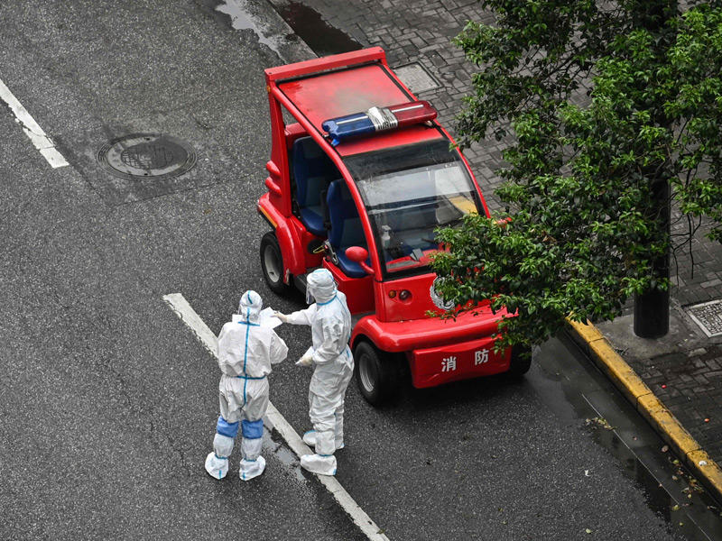 ضباط يرتدون معدات الحماية الشخصية يقفون في أحد الشوارع خلال إغلاق فيروس كورونا في منطقة جينغان في شنغهاي (AFP)