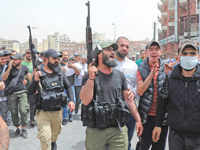 مسلحون خلال تشييع بعض ضحايا «قارب الموت» في طرابلس أمس (رويترز)