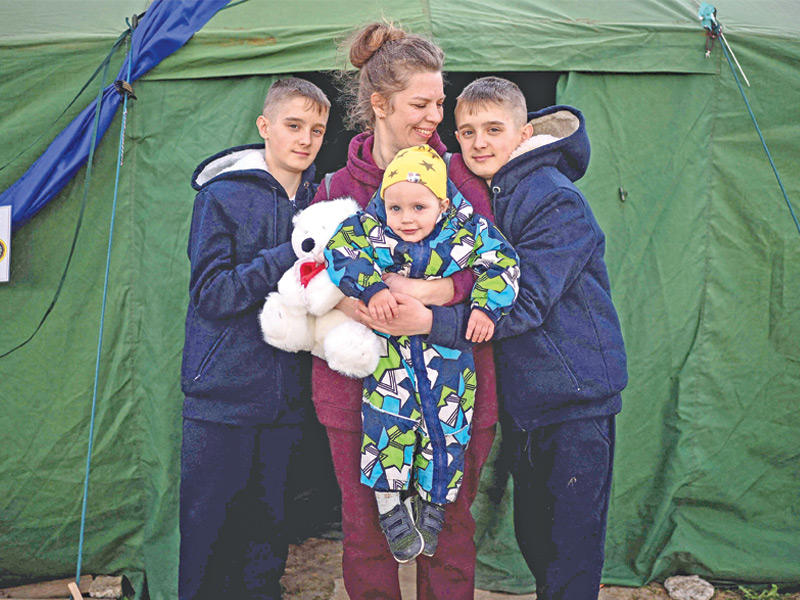 عائلة أوكرانية أمام خيمتهم في مخيّم للاجئين على الحدود السلوفاكية (أ ف ب)