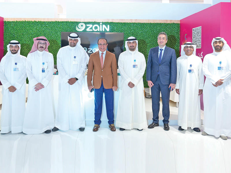 العثمان يتوسط مسؤولي «زين» في جناح الشركة بالمعرض
