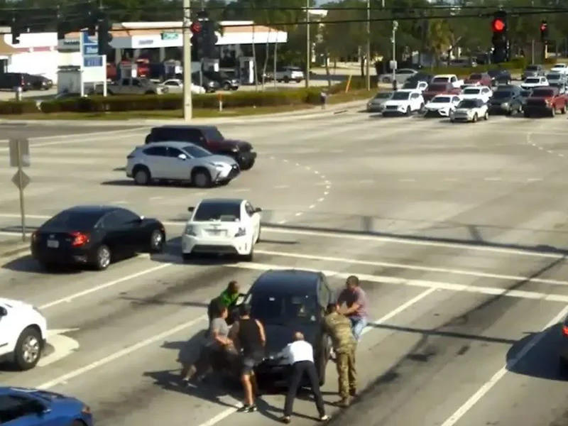 مجموعة من المارة محاولين فتح الباب لانقاذ المرأة