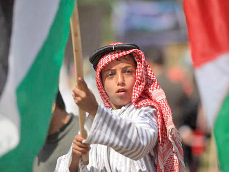 طفل فلسطيني يرفع علم بلاده