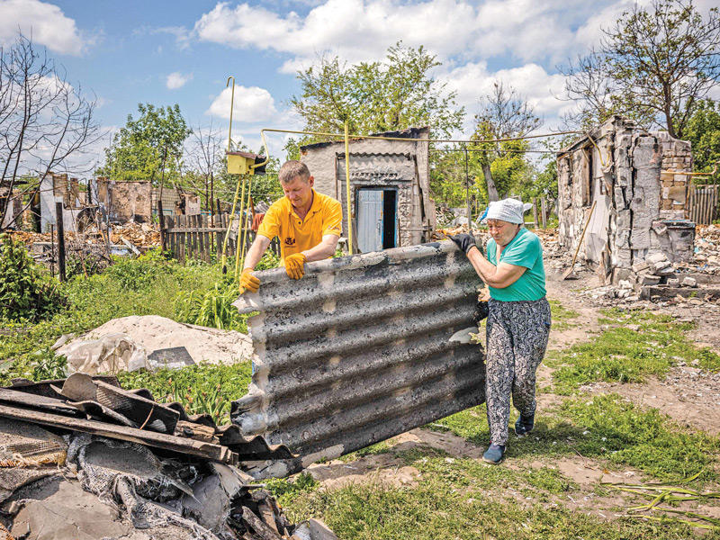 امرأة مسنّة وابنها يزيلان بقايا منزلهما المحترق في قرية أندرييفكا (أ ف ب)