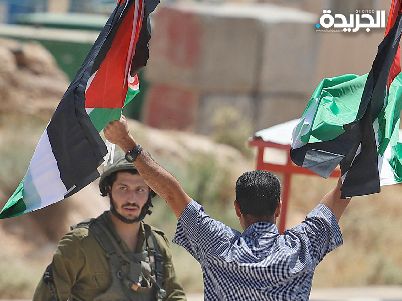 مواطن فلسطيني يرفع علم فلسطين بوجه جندي احتلال