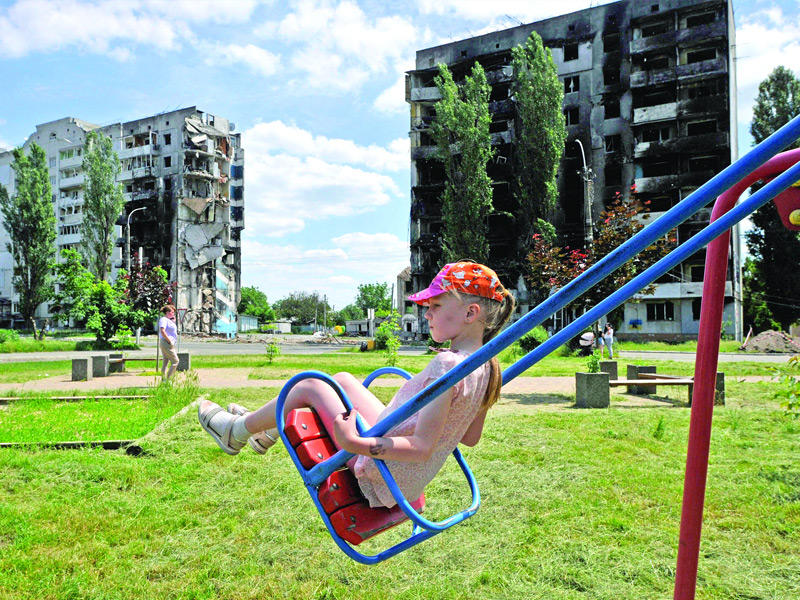 طفلة أوكرانية تلهو على أرجوحة أمام مبنى مدمر في بورودينكا    (أ ف ب)