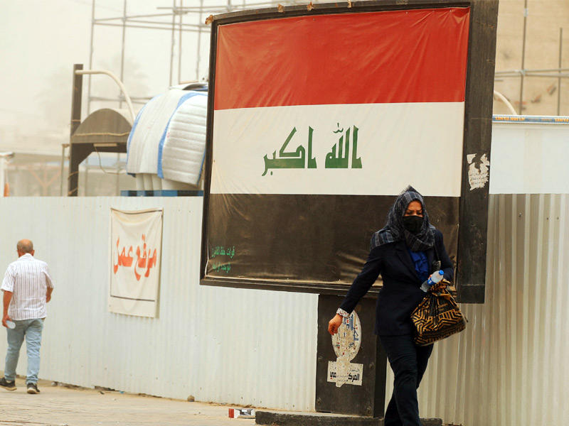 عراقية تغطي وجهها من الغبار في بغداد أمس (أ ف ب)