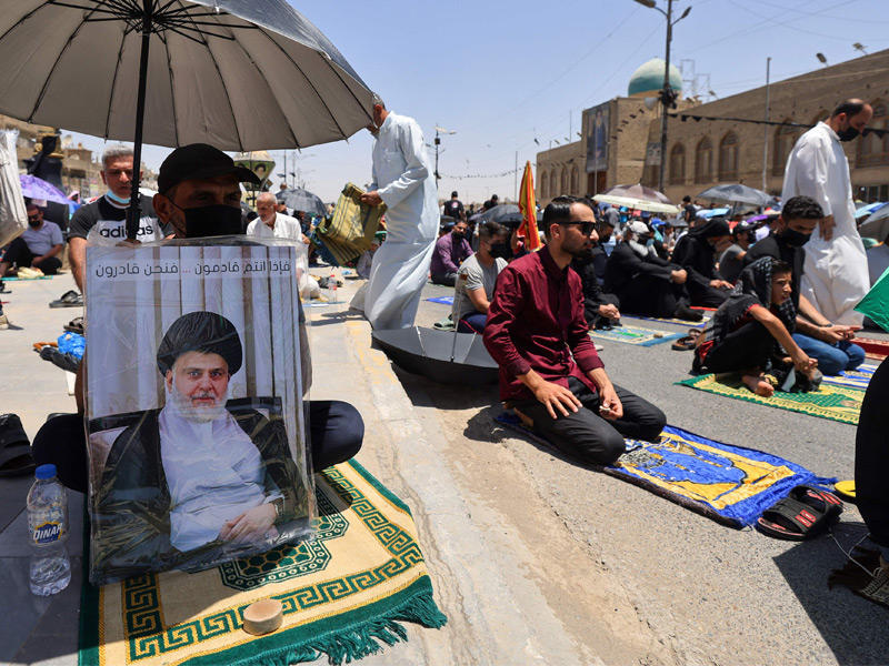 أنصار الصدر يرفعون صوره خلال صلاة الجمعة في مدينة الصدر (أ ف ب)