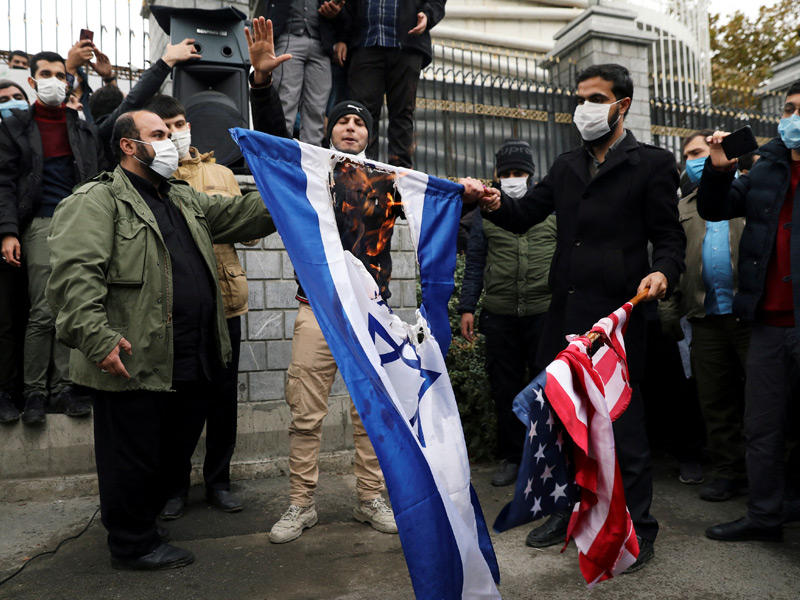 متظاهرون يحرقون العلمين الأميركي والإسرائيلي خلال تظاهرة في طهران (رويترز)