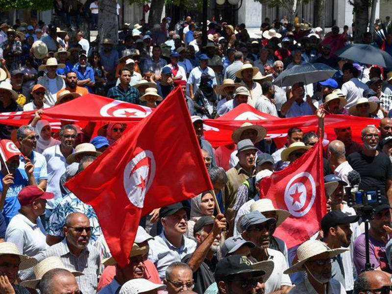 متظاهرون تونسيون يرفعون الأعلام الوطنية خلال مظاهرة في العاصمة تونس في 19 يونيو 2022 ضد الرئيس قيس سعيد 