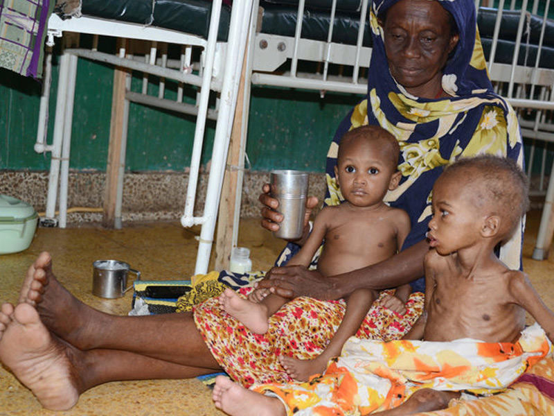 أم تجلس مع طفليها الذين يعانون من سوء التغذية في مستشفى بنادير في مقديشو 