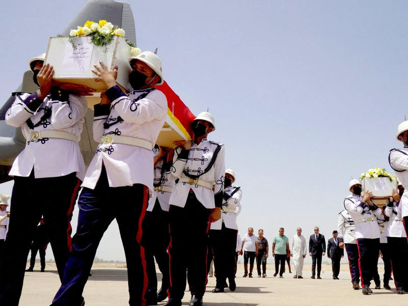 عناصر من «حرس الشرف» يحملون نعوش ضحايا الهجوم لدى وصولها إلى مطار بغداد أمس (رويترز)