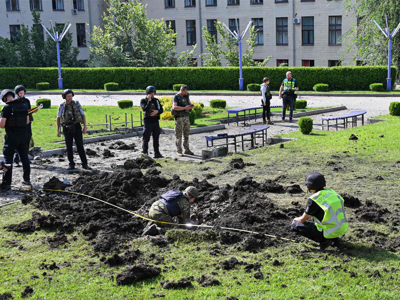 خبراء من الشرطة الأوكرانية يتفقدون حفرة نتجت عن انفجار قذيفة في خاركيف أمس (أ ف ب)