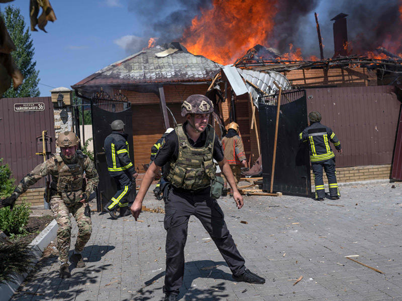 جنود ورجال إطفاء أوكرانيون قرب منزل يحترق بعد إصابته بقذيفة روسية في ضواحي باخموت أمس (أ ف ب)