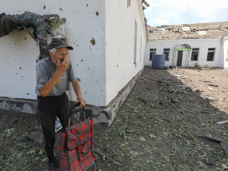 أوكراني يبكي قرب مدرسة مدمّرة في ميكولايف أمس (رويترز)
