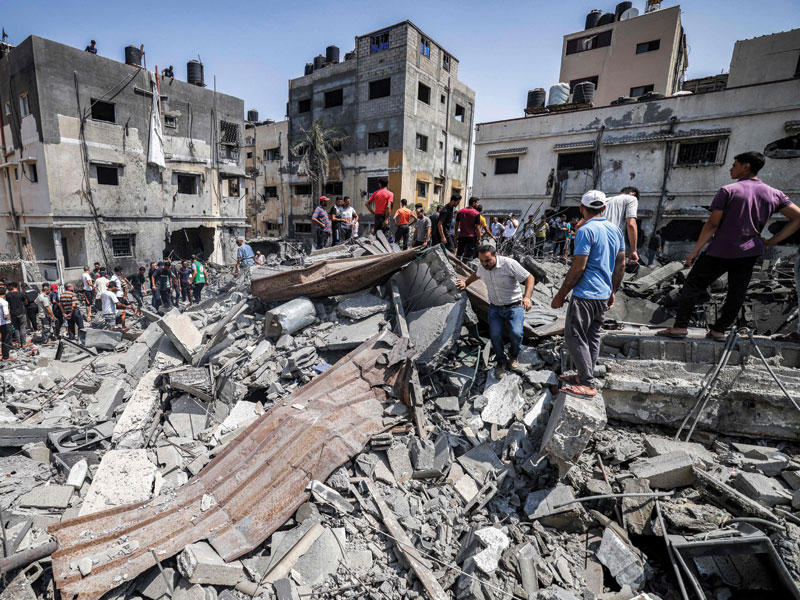 فلسطينيون يتفحصون مباني دمرتها غارات إسرائيل على غزة (أ ف ب)