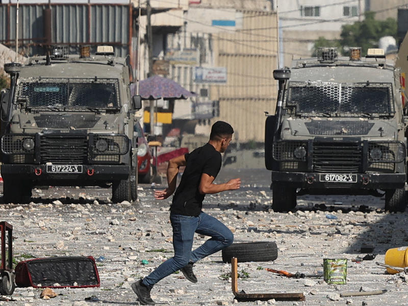 فلسطيني يواجه القوات الإسرائيلية في نابلس أمس  (أ ف ب)