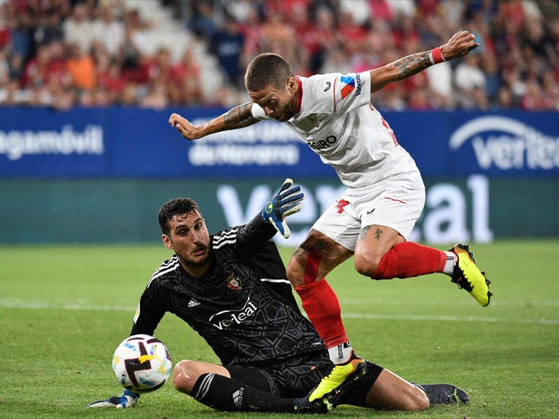 لاعب إشبيلية غوميز يحاول المرور من حارس أوساسونا هيريرا (أ ف ب)