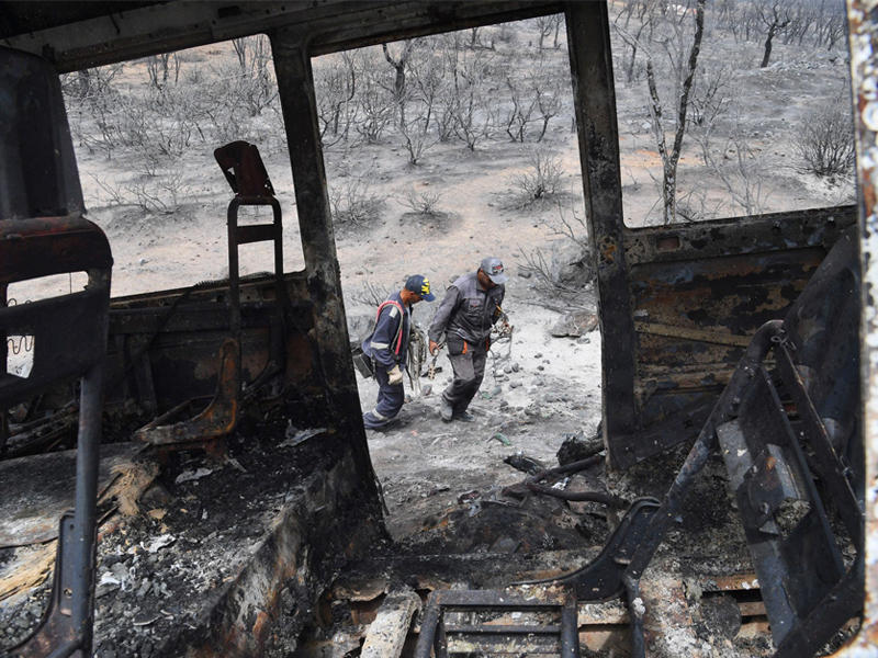 عنصرا إطفاء يمران قرب شاحنة التهمتها النيران في منطقة الكلا أمس (أ ف ب)