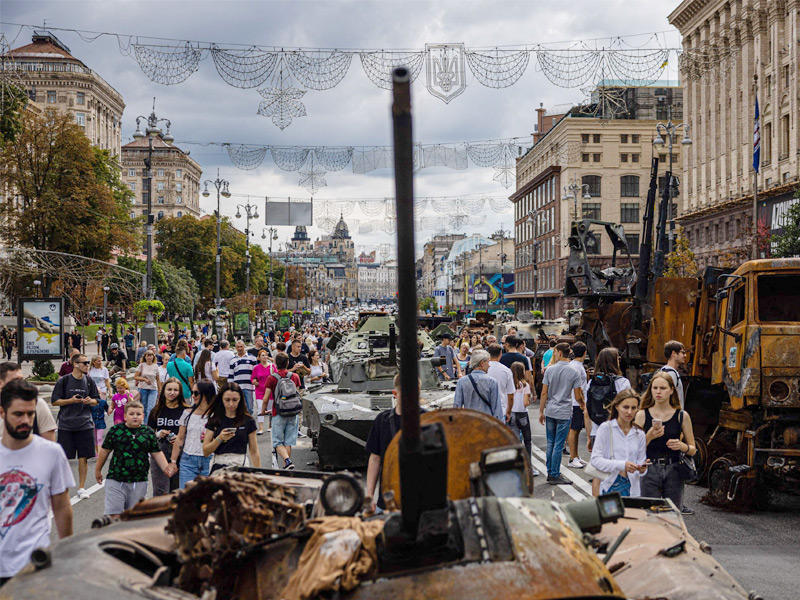 أوكرانيون قرب آليات روسية متفحمة وسط كييف (أ ف ب)