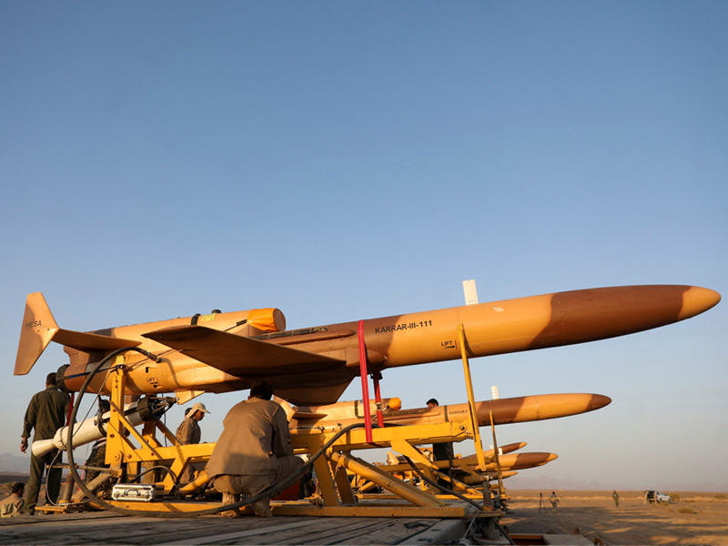 عسكريون يجهزون مسيرات حربية خلال مناورات تشمل عدة مناطق في إيران أمس (رويترز)